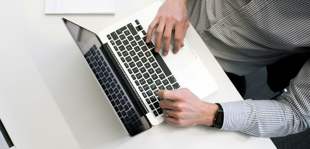 Person working on a laptop at a white desk